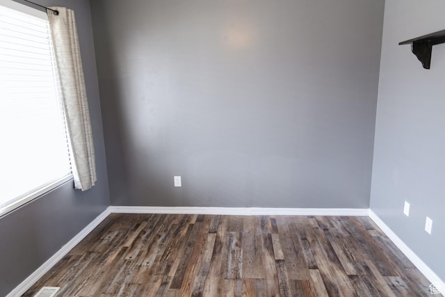 empty room featuring visible vents, baseboards, and wood finished floors