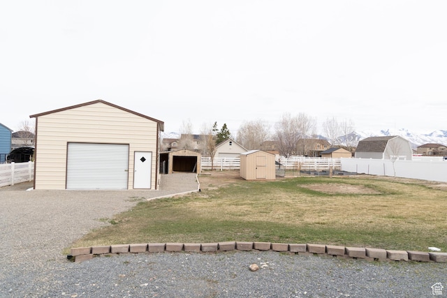 view of yard with an outdoor structure, driveway, fence, and a storage shed