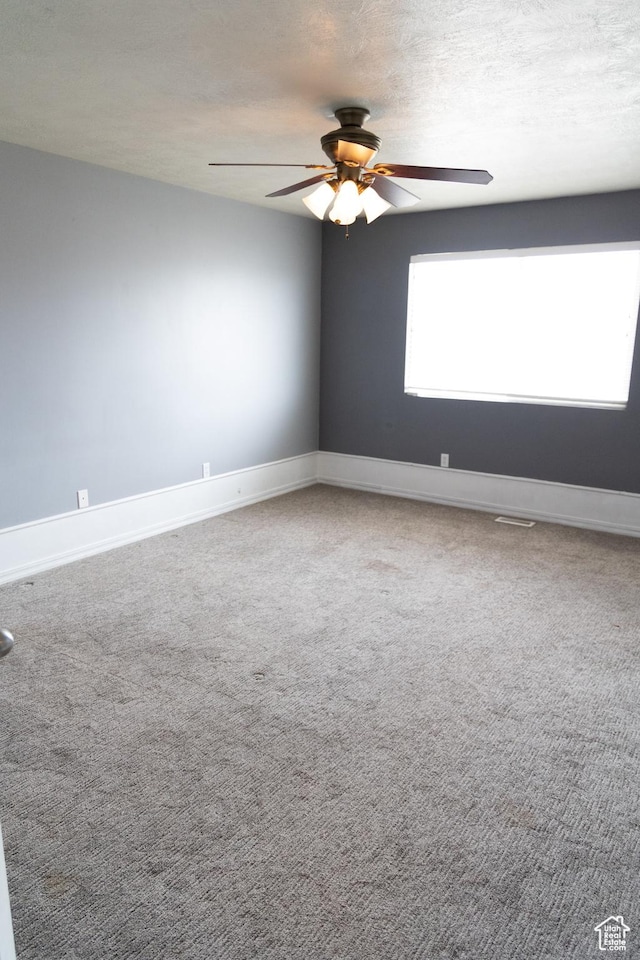 unfurnished room featuring baseboards, a textured ceiling, a ceiling fan, and carpet