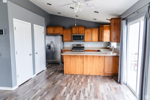 kitchen with light countertops, a sink, stainless steel appliances, and brown cabinetry