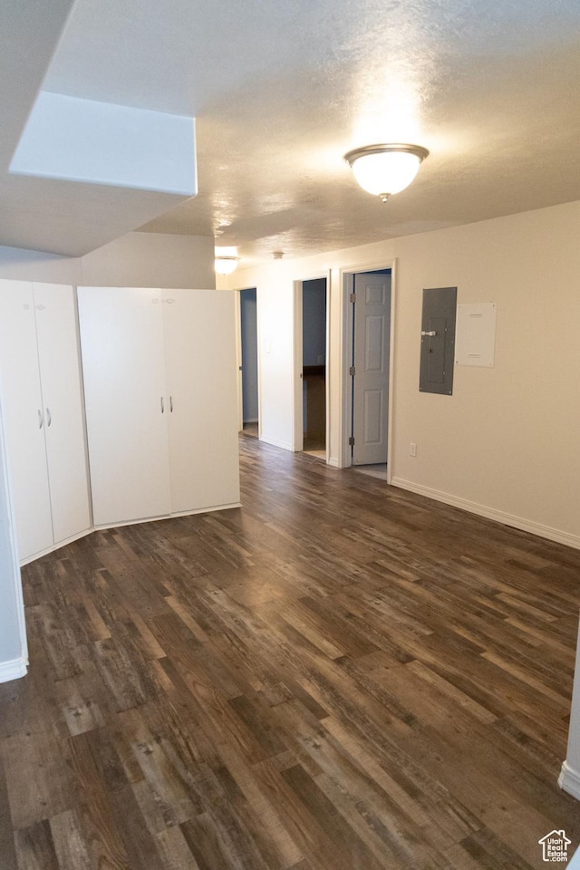 interior space featuring baseboards, a textured ceiling, electric panel, and dark wood finished floors