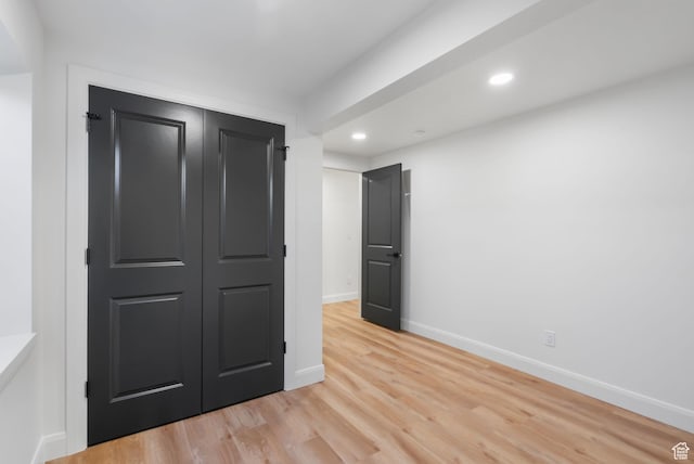 unfurnished bedroom with baseboards, a closet, light wood-style flooring, and recessed lighting
