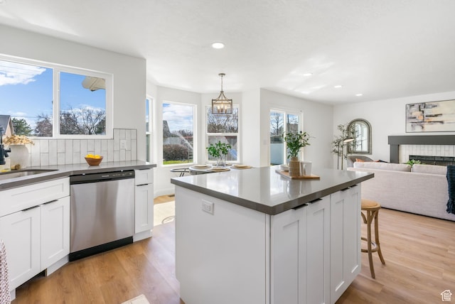 kitchen featuring a sink, tasteful backsplash, dishwasher, light wood-type flooring, and dark countertops