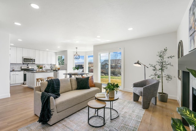 living room featuring baseboards, recessed lighting, and light wood-type flooring