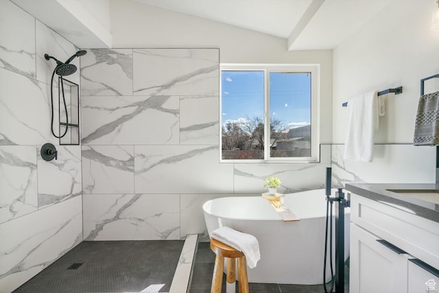 full bath with vanity, a freestanding tub, a marble finish shower, and vaulted ceiling