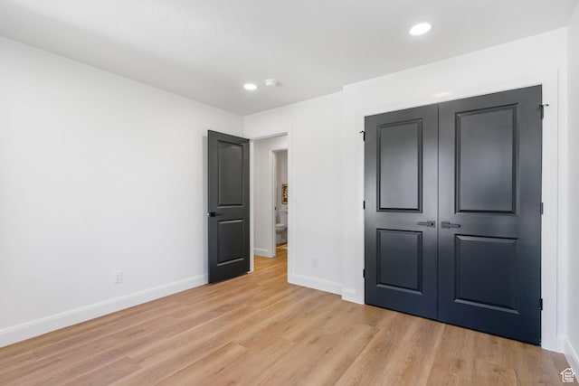unfurnished bedroom featuring a closet, baseboards, light wood-style floors, and recessed lighting