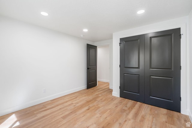 unfurnished bedroom with recessed lighting, a closet, baseboards, and light wood-type flooring