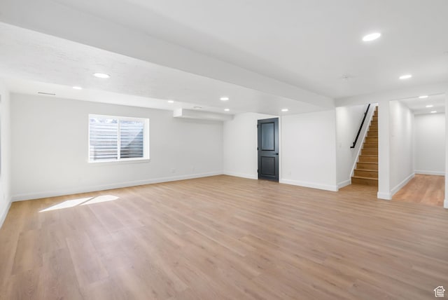 basement with baseboards, stairs, recessed lighting, and light wood-style floors