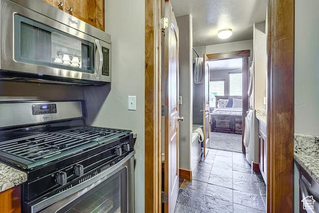 3518 N Moose Hollow Dr, Eden, UT 84310 - kitchen with brown cabinets, stainless steel appliances, stone tile floors, and light stone counters