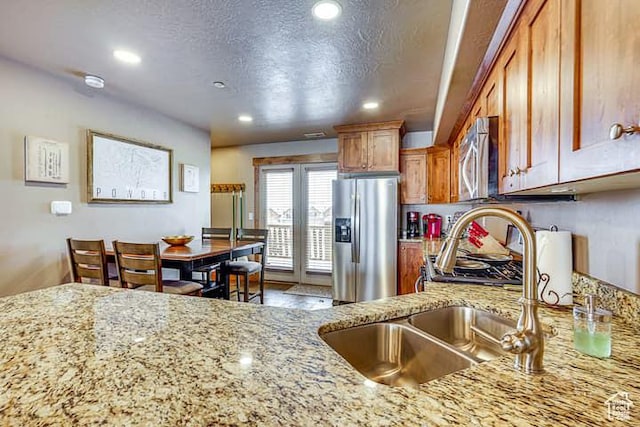 3518 N Moose Hollow Dr, Eden, UT 84310 - kitchen with a textured ceiling, a sink, light stone countertops, appliances with stainless steel finishes, and brown cabinetry