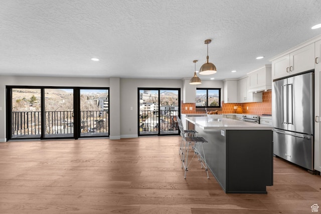 245 N Vine St W Unit 903, Salt Lake City, UT 84103 - kitchen featuring light countertops, backsplash, light wood-style floors, white cabinets, and appliances with stainless steel finishes