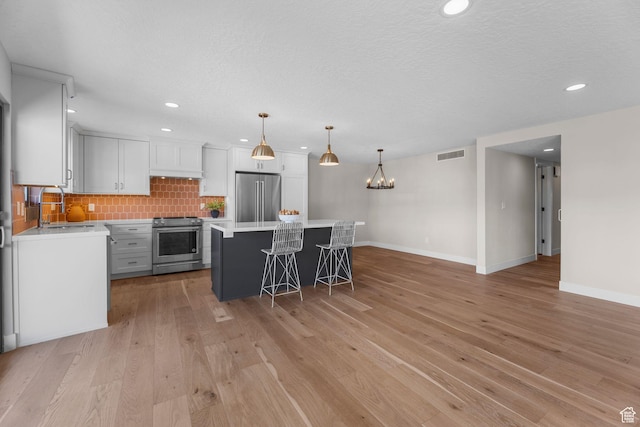 245 N Vine St W Unit 903, Salt Lake City, UT 84103 - kitchen featuring visible vents, a kitchen bar, tasteful backsplash, appliances with stainless steel finishes, and a sink