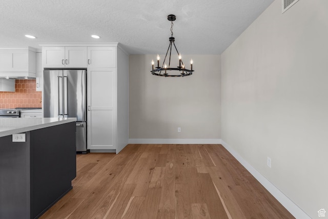245 N Vine St W Unit 903, Salt Lake City, UT 84103 - unfurnished dining area with recessed lighting, an inviting chandelier, baseboards, a textured ceiling, and light wood-style floors