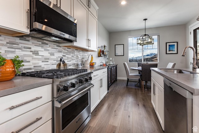 6065 N Westridge Rd, Heber City, UT 84032 - kitchen featuring appliances with stainless steel finishes, tasteful backsplash, dark wood finished floors, a sink, and an inviting chandelier
