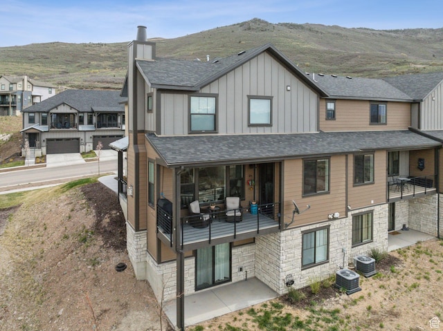 6065 N Westridge Rd, Heber City, UT 84032 - rear view of property with stone siding, board and batten siding, a chimney, cooling unit, and a balcony