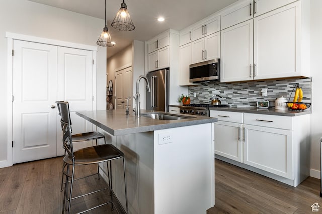 6065 N Westridge Rd, Heber City, UT 84032 - kitchen featuring dark countertops, a sink, an island with sink, stainless steel appliances, and tasteful backsplash