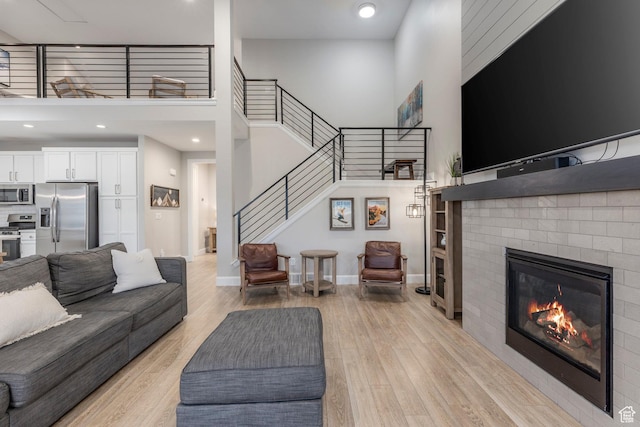 1089 W Cattail Ct, Kamas, UT 84036 - living area with a fireplace, light wood-style flooring, stairs, a high ceiling, and baseboards