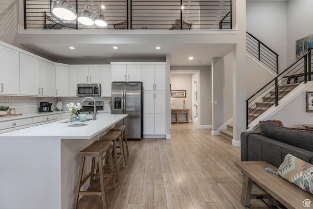 1089 W Cattail Ct, Kamas, UT 84036 - kitchen with stainless steel appliances, a towering ceiling, light wood finished floors, light countertops, and white cabinetry