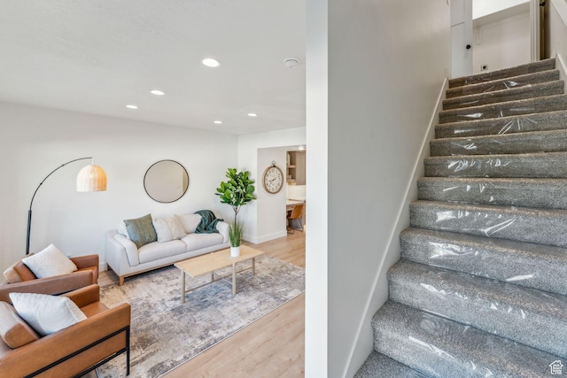 stairway with baseboards, wood finished floors, and recessed lighting