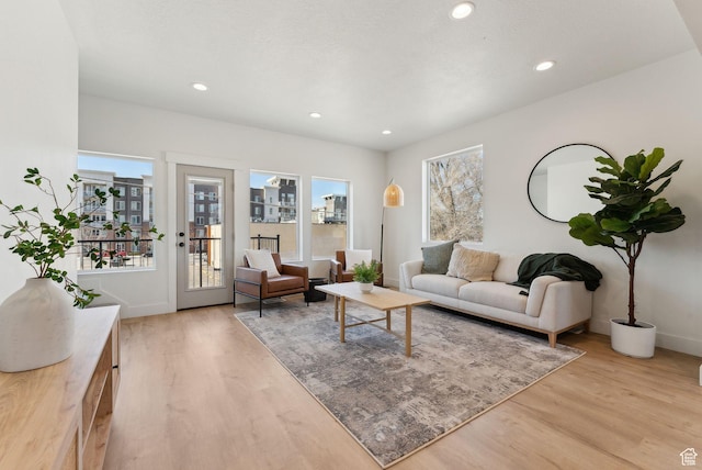 living area featuring baseboards, recessed lighting, light wood-style floors, and a city view