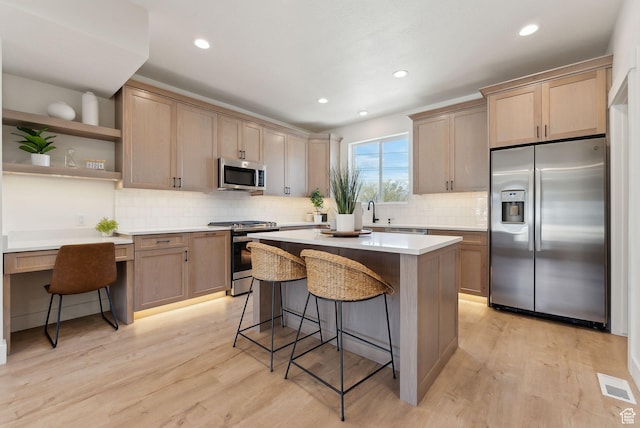 kitchen with light wood-style flooring, a breakfast bar area, visible vents, and stainless steel appliances