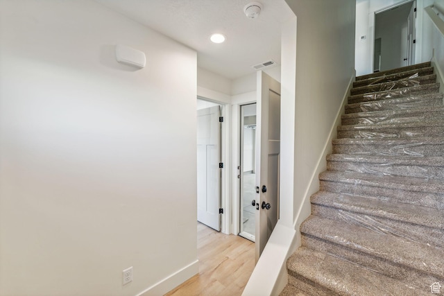 staircase with baseboards, visible vents, wood finished floors, and recessed lighting
