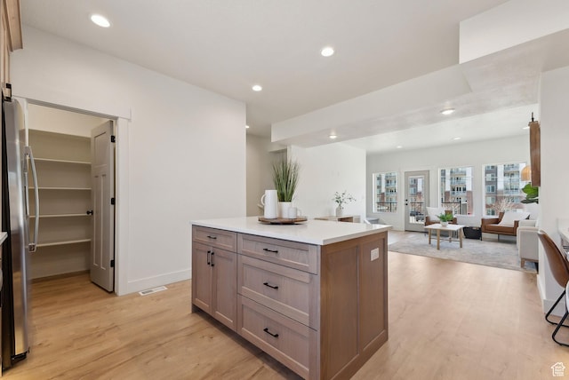 kitchen with freestanding refrigerator, a center island, open floor plan, light wood-style floors, and recessed lighting