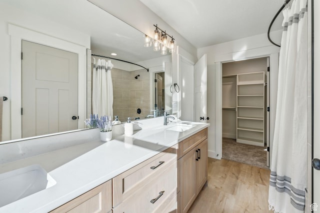 full bath with a shower with curtain, a spacious closet, wood finished floors, and vanity