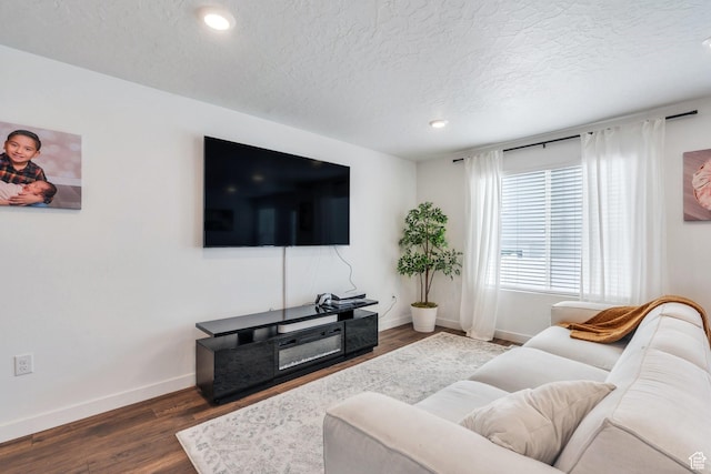 living area featuring baseboards, a textured ceiling, dark wood-style floors, and recessed lighting