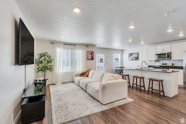 living area featuring dark wood-style floors, recessed lighting, baseboards, and a textured ceiling