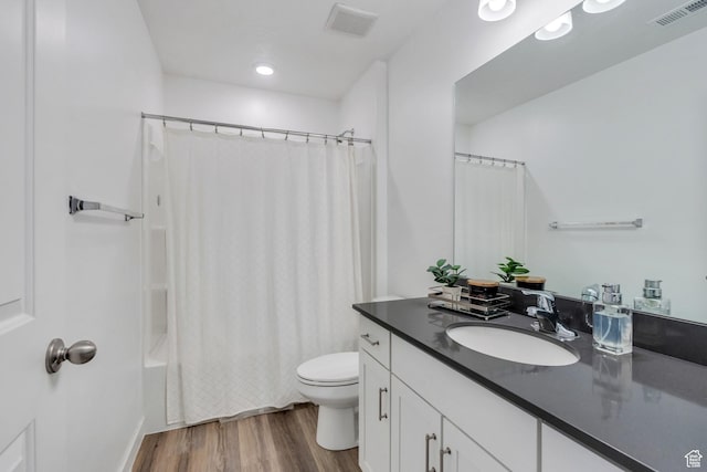 full bath with toilet, vanity, wood finished floors, and visible vents