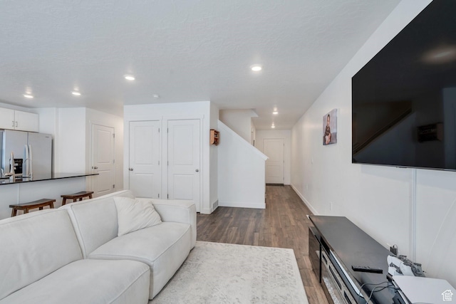living area featuring baseboards, wood finished floors, recessed lighting, and a textured ceiling