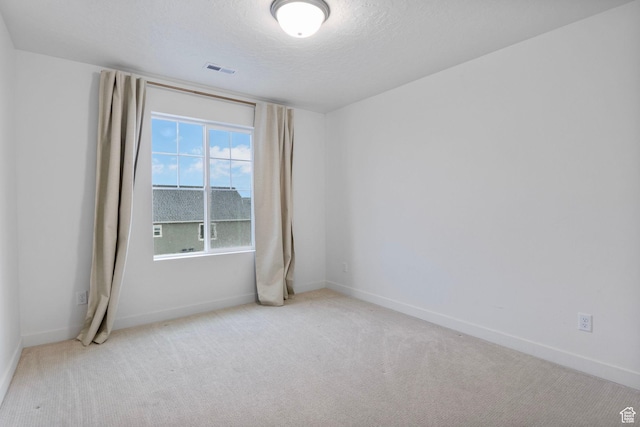 carpeted spare room with baseboards, a textured ceiling, and visible vents