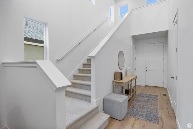 stairway featuring a towering ceiling and wood finished floors