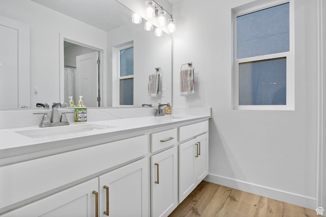 bathroom with double vanity, a sink, baseboards, and wood finished floors