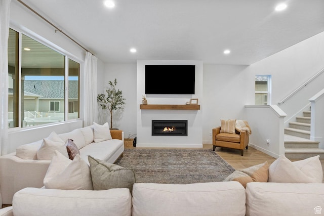 living room with baseboards, stairs, wood finished floors, recessed lighting, and a glass covered fireplace