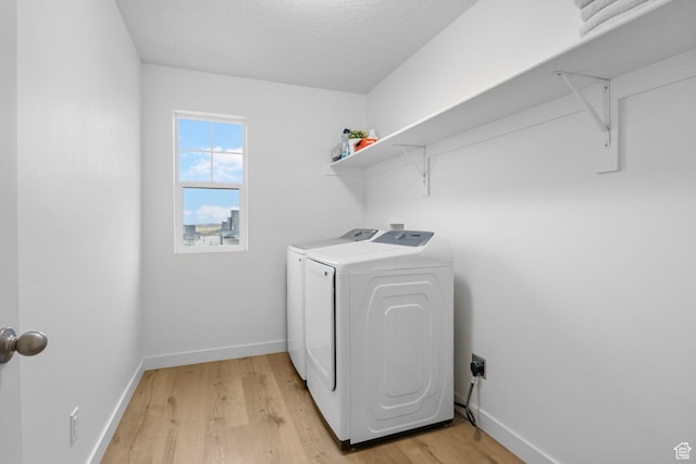 washroom with baseboards, washing machine and dryer, light wood-style flooring, and laundry area
