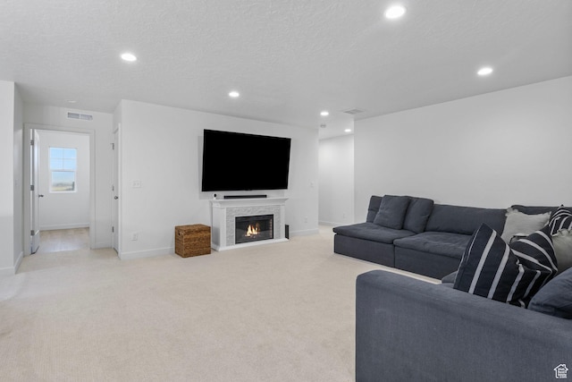 living room featuring a textured ceiling, visible vents, recessed lighting, and light colored carpet