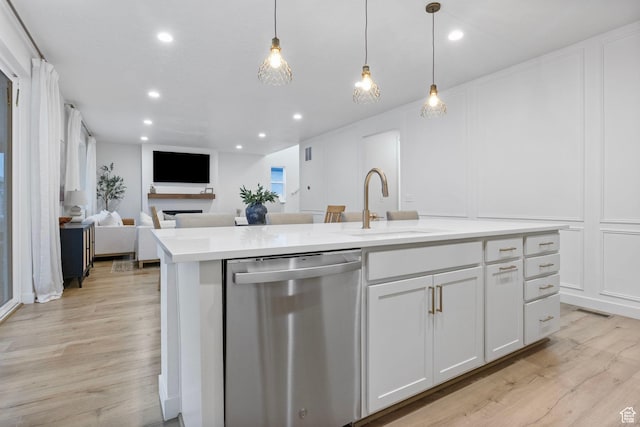 kitchen with a decorative wall, white cabinets, a sink, light wood-style floors, and stainless steel dishwasher