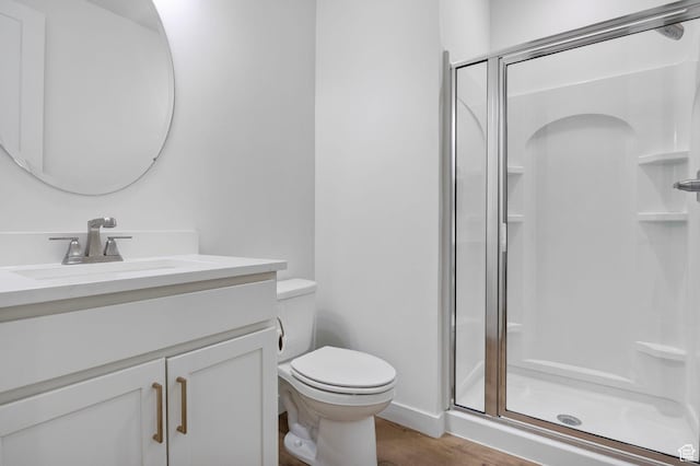 full bath featuring vanity, toilet, a shower stall, and wood finished floors