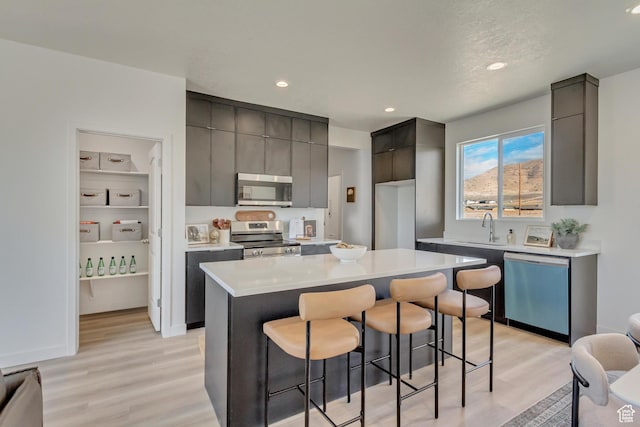 2398 E Cinder Ln, Eagle Mountain, UT 84005 - kitchen with light countertops, a sink, a kitchen breakfast bar, appliances with stainless steel finishes, and modern cabinets