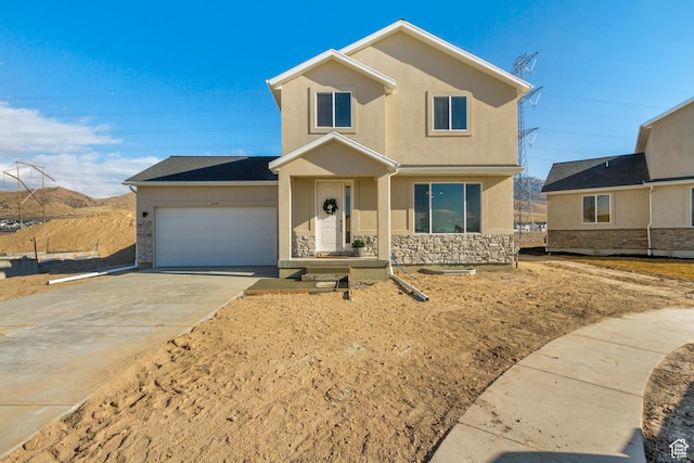 traditional-style house featuring driveway, stucco siding, an attached garage, and stone siding