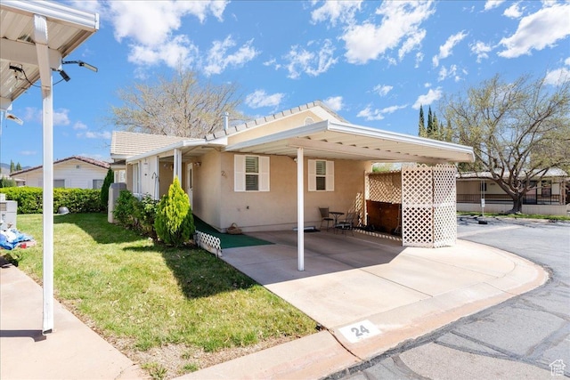 view of property exterior featuring an attached carport, concrete driveway, stucco siding, and a yard