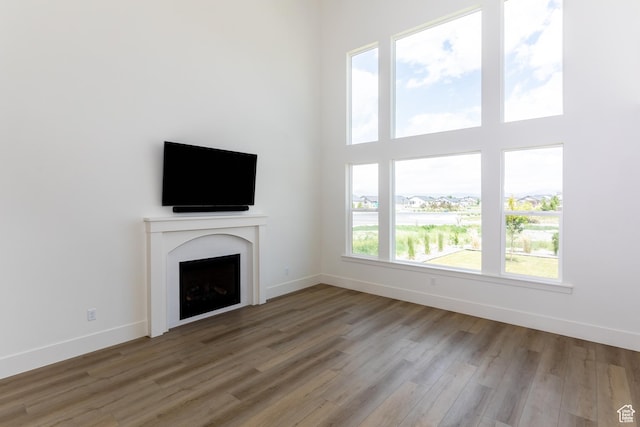 unfurnished living room with baseboards, a fireplace, and wood finished floors
