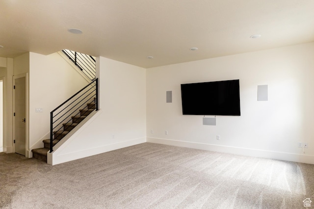 unfurnished living room with baseboards, stairway, and carpet flooring