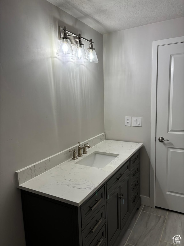 12038 S Middle Teton Dr Unit 134, Herriman, UT 84096 - bathroom with a textured ceiling, vanity, baseboards, and marble finish floors