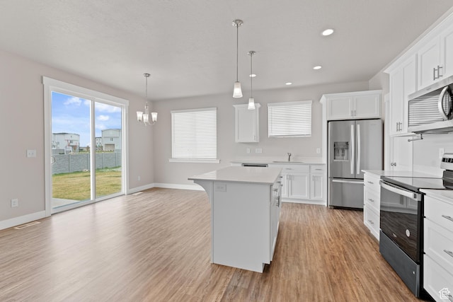 kitchen featuring light wood-style floors, light countertops, a sink, a notable chandelier, and stainless steel appliances