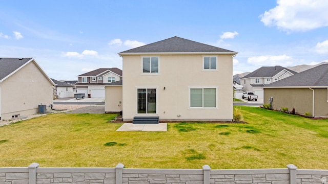 back of property with fence, stucco siding, entry steps, a lawn, and a residential view