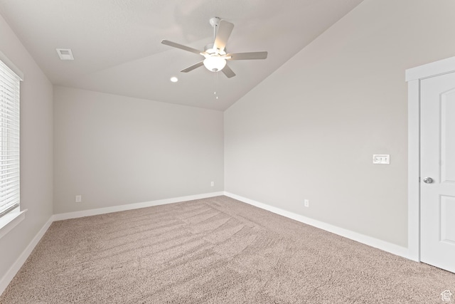 carpeted spare room featuring baseboards, a ceiling fan, vaulted ceiling, and visible vents