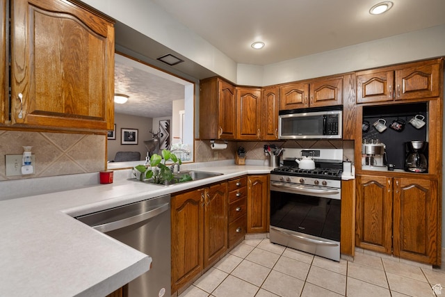 kitchen featuring tasteful backsplash, brown cabinets, light tile patterned floors, light countertops, and stainless steel appliances